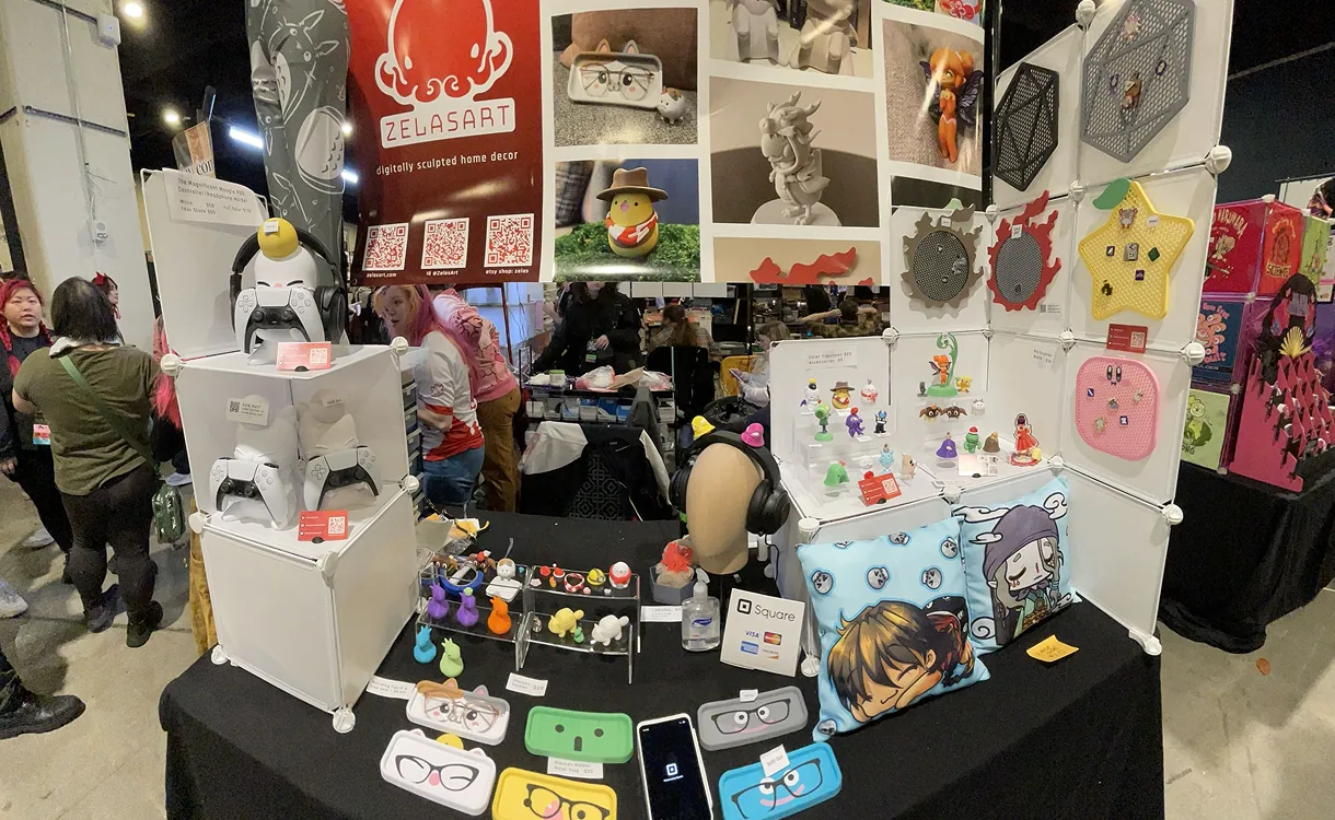 Full ZELASART convention booth with figures, displays, and banner